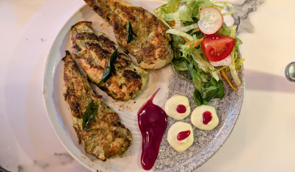 Khandari Chicken served on a plate with salad and sauce.